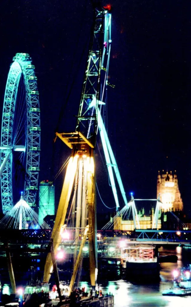 Taklift 3 is seen installing the A-frame pylon at Hungerford Bridge, with the London Eye and the Houses of Parliament in the background.
