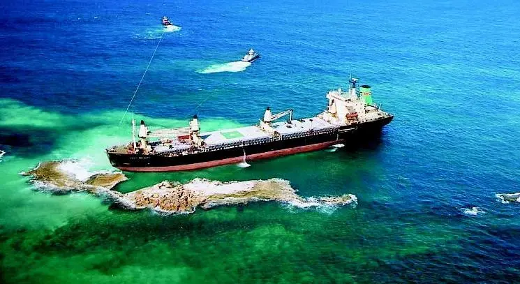 Tugs work together to pull the vessel from the rocks.