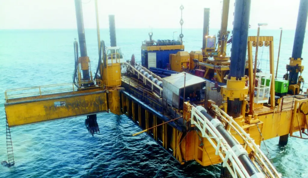 The pipeline is guided into the trench dug by the pontoons integral grab.