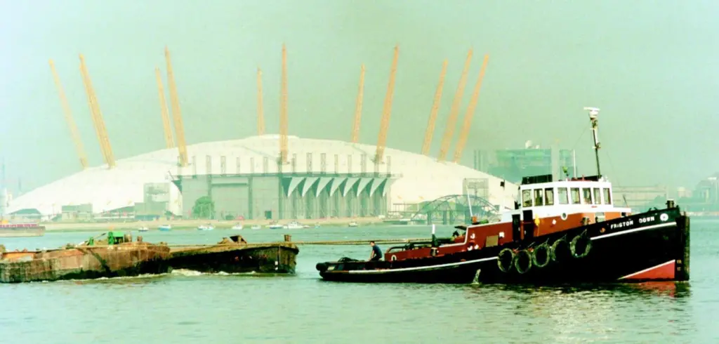The GPS tug Friston Down tows a string of barges up river past the Millennium Dome.