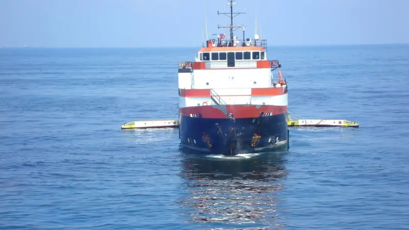 A sweeping arm system fitted to a commercial vessel collects oil in the Gulf of Mexico.