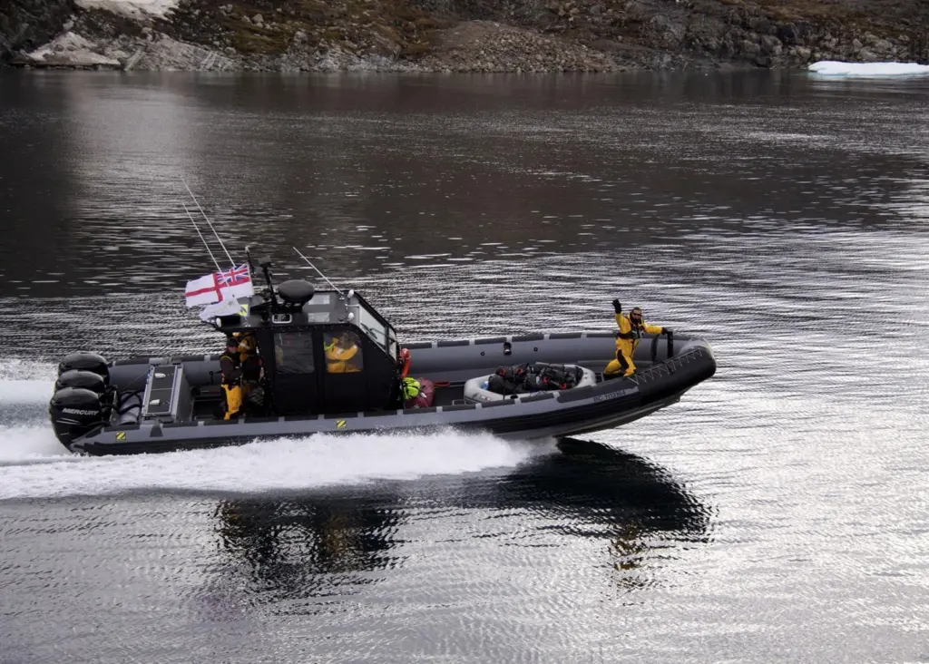 Bear Grylls waves from the bow of the RIB as it transits smooth water at more than 40 knots.