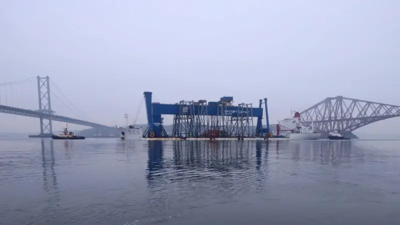 The Goliath crane is seen on its delivery vessel between the Forth road and rail bridges as it approaches the Rosyth dockyard.
