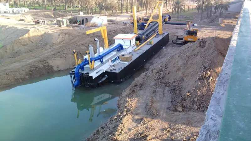 A cutter suction dredger has been assembled and is launched at a job site.