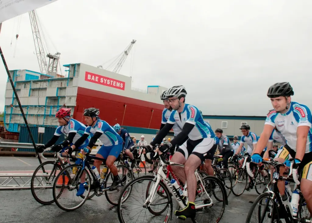 Charity ride cyclists leave BAE Systems’ Govan shipyard, with Lower Block 03 seen in the background.