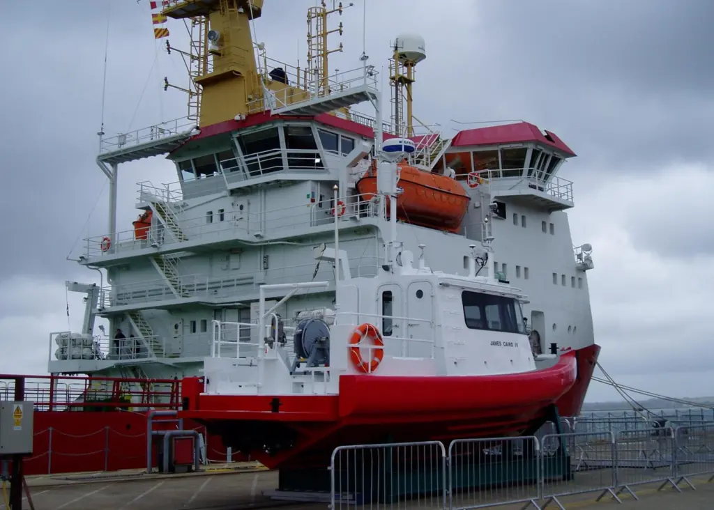 SMB James Caird IV is seen on the quay with mothership HMS Protector alongside.