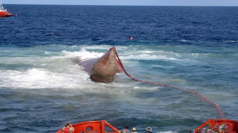 Rising from a depth of 110 feet, the bow of the Angeln container vessel is seen breaking the surface during the refloating operation.
