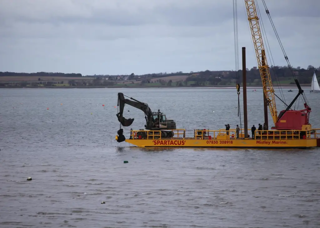 A bucket grab crane mounted on Mistley Marine's flat top barge Spartacus salvages the rocket remains.