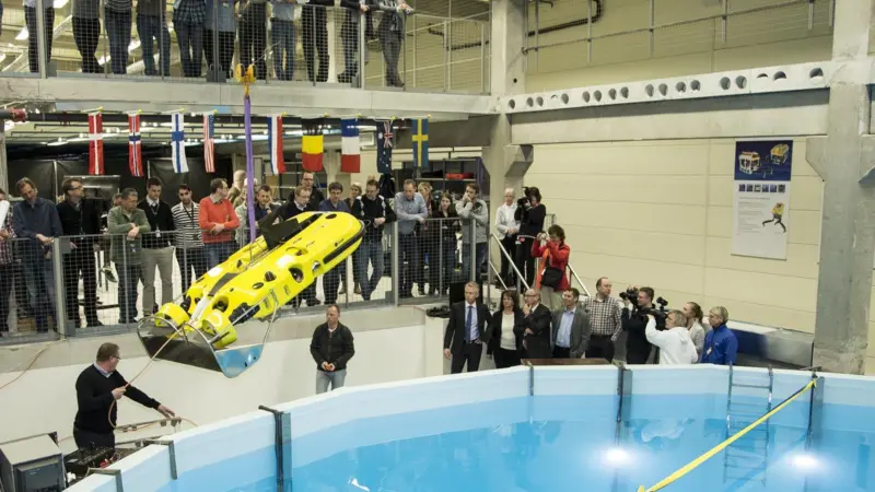 An underwater vehicle is lowered into the new test tank in preparation for opening ceremony