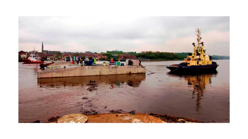 A tug is seen moving the pontoon away from its build site at Neptune Energy Park
