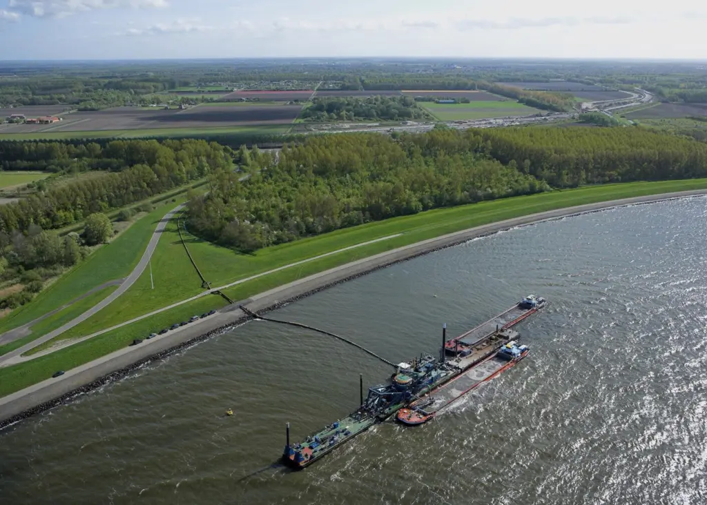 Supply barges provide sand which is pumped to the works site