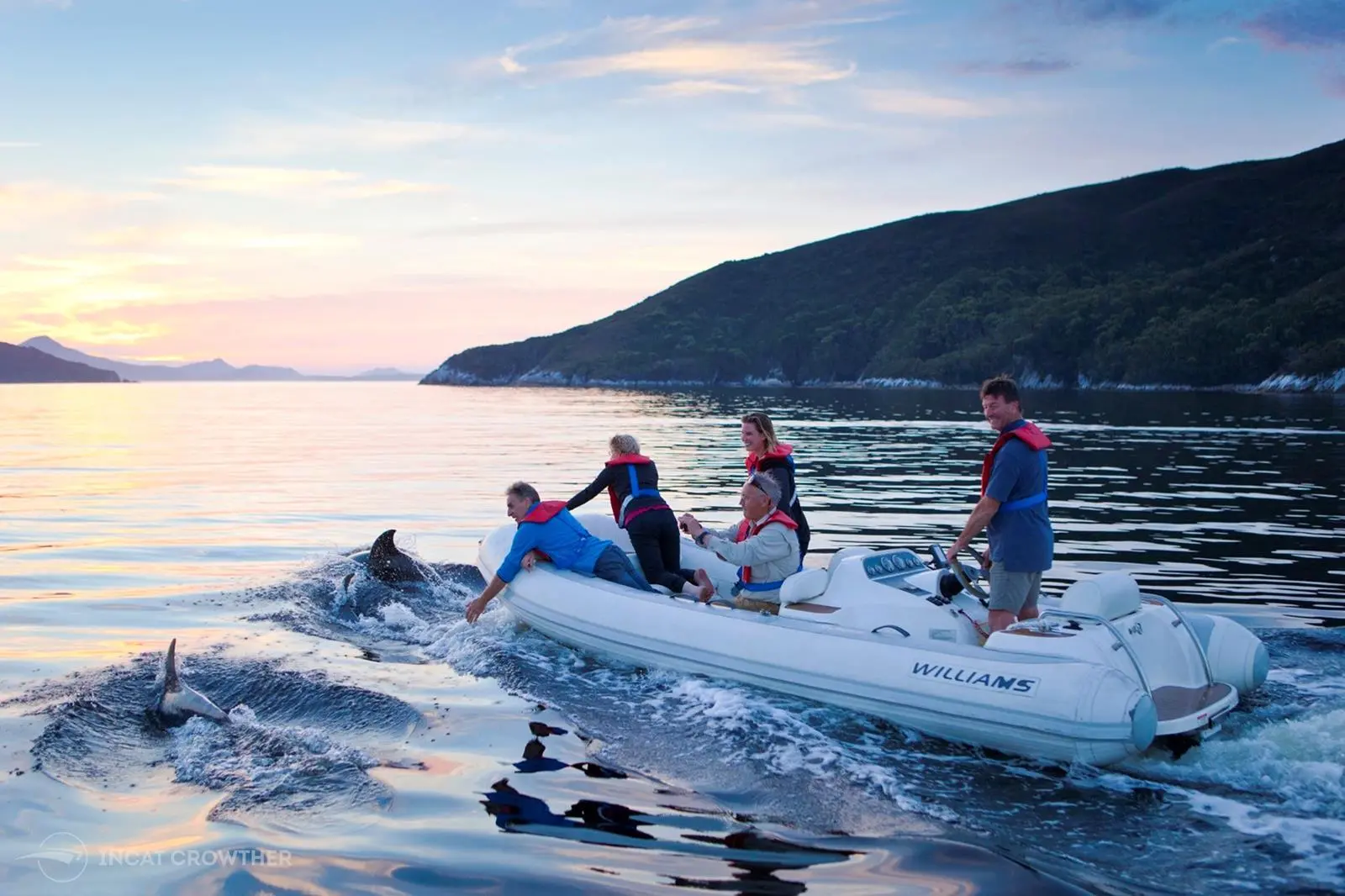 ic20233-9-9-01-guests-in-the-jetboat-are-joined-by-dolphins-at-sunset-editors-to-credit-mark-daffey
