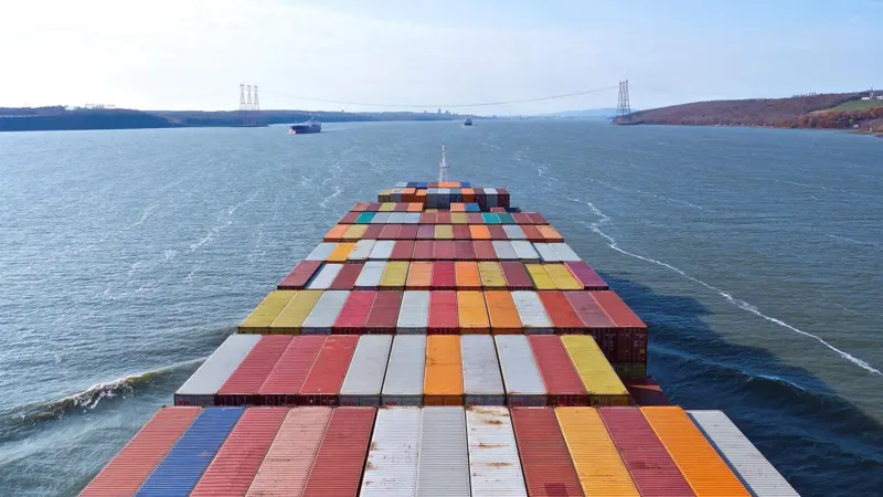 Image shows the view from the front of a container ship at sea with the deck full of cargo