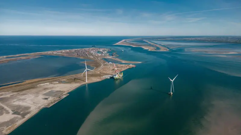 Aerial shot of Thyborøn Port in Denmark two wind turbines and a service vessel at dock