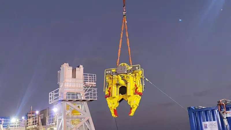 Decom Engineering's C1-24 Chopsaw in action. The saw is suspended above a ship's deck with workers
