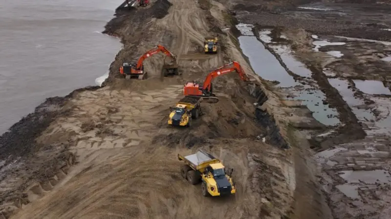 Construction vehicles breaching a dyke at the Scheldt river in Antwerp