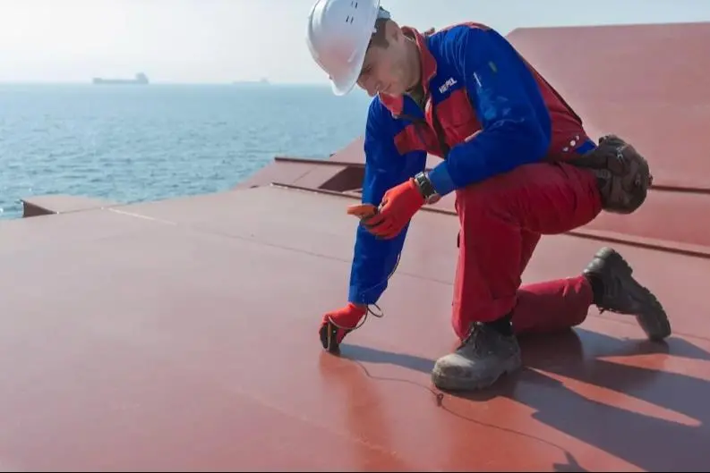 The image shows a worker testing the efficacy of Hempel marine coatings