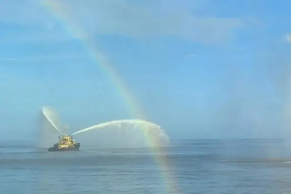 The image shows a firefighting tug in action on the water