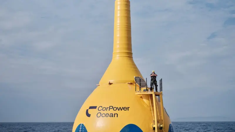 A giant CorPower Ocean yellow buoy with a man standing on top