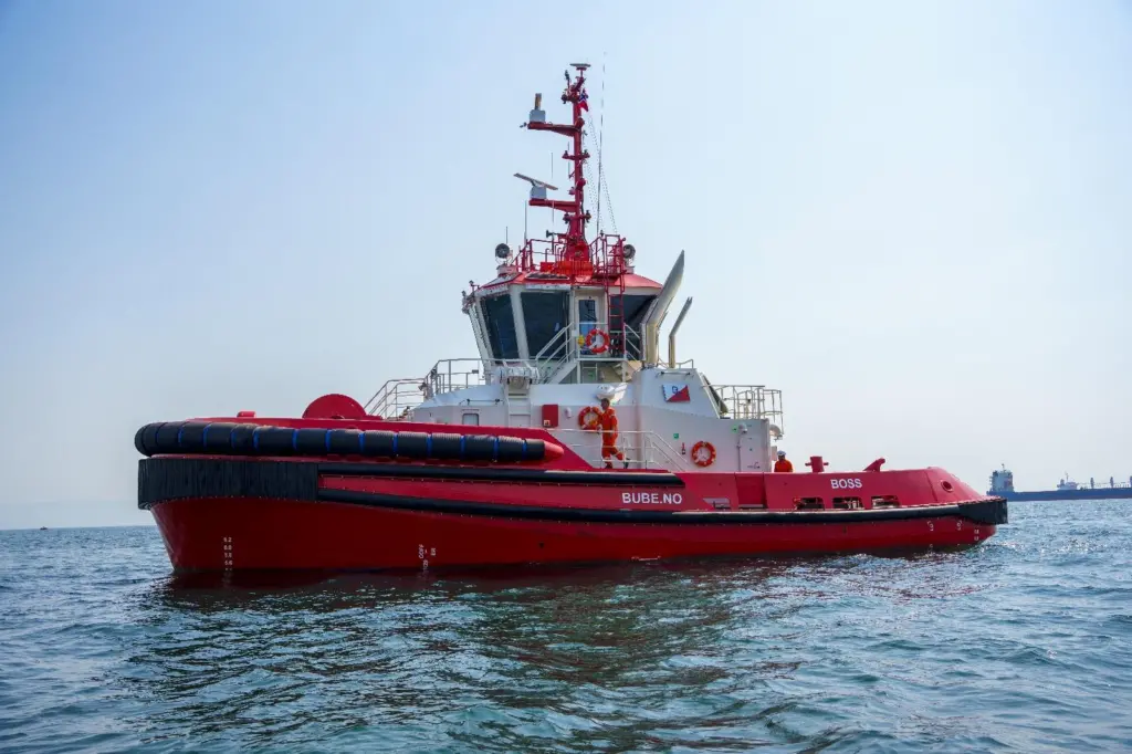A red and white tugboat named 'BOSS' at sea