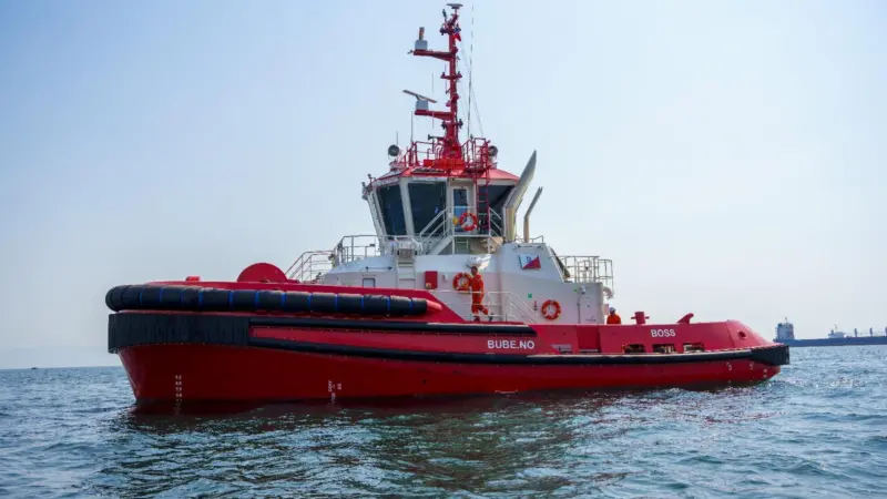 A red and white tugboat named 'BOSS' at sea