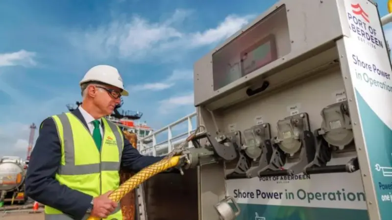 The image shows an high-vis engineer in front of the shore power facilities at Aberdeen