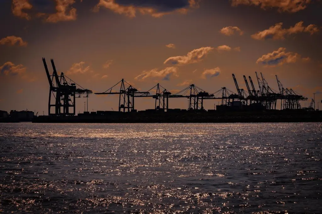 The image shows port cranes at sunset