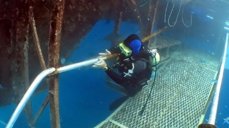 The image shows a diver performing an underwater inspection