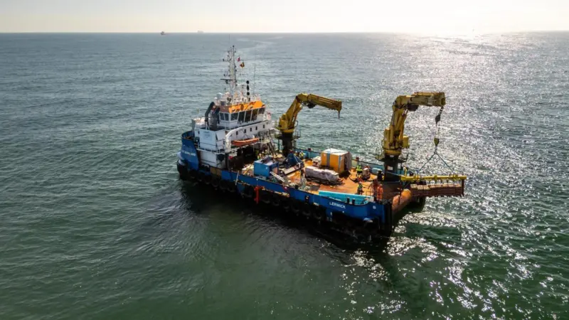 The image shows Jan De Nul's Voe Vanguard Multicat vessel at sea during the project