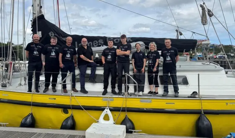 The image shows the NSSLGlobal team with the crew onboard the Ocean Youth Trust North’s yacht James Cook