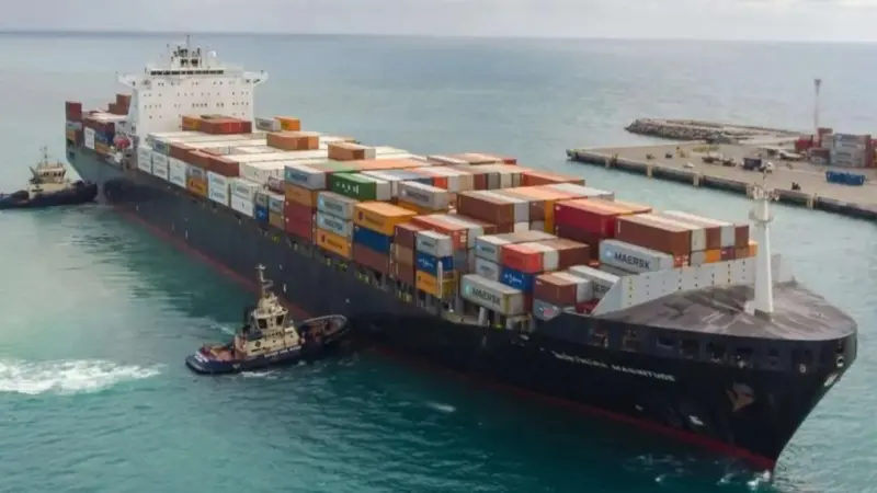 The image shows Svitzer tugs guiding a container ship into port
