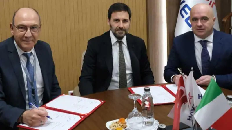 The image shows parties from the three companies signing the MoU